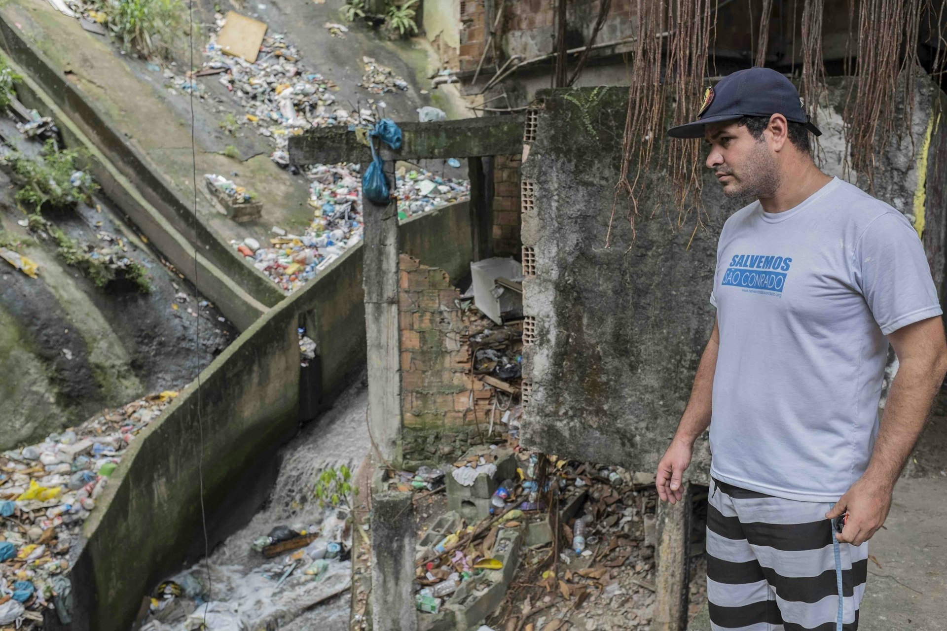 Marcello Farias in front of a polluted drain in Lajão, Rocinha.