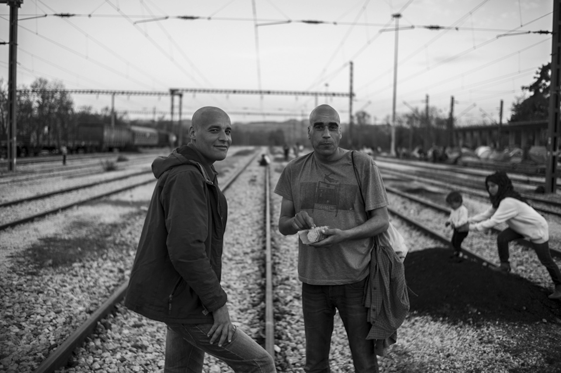  Karim (left) and Hassan (right) from Algeria, standing in the centre of the tracks outside Idomeni Station. An outbreak of lice in the camp means many of the residents have shaved their heads. 