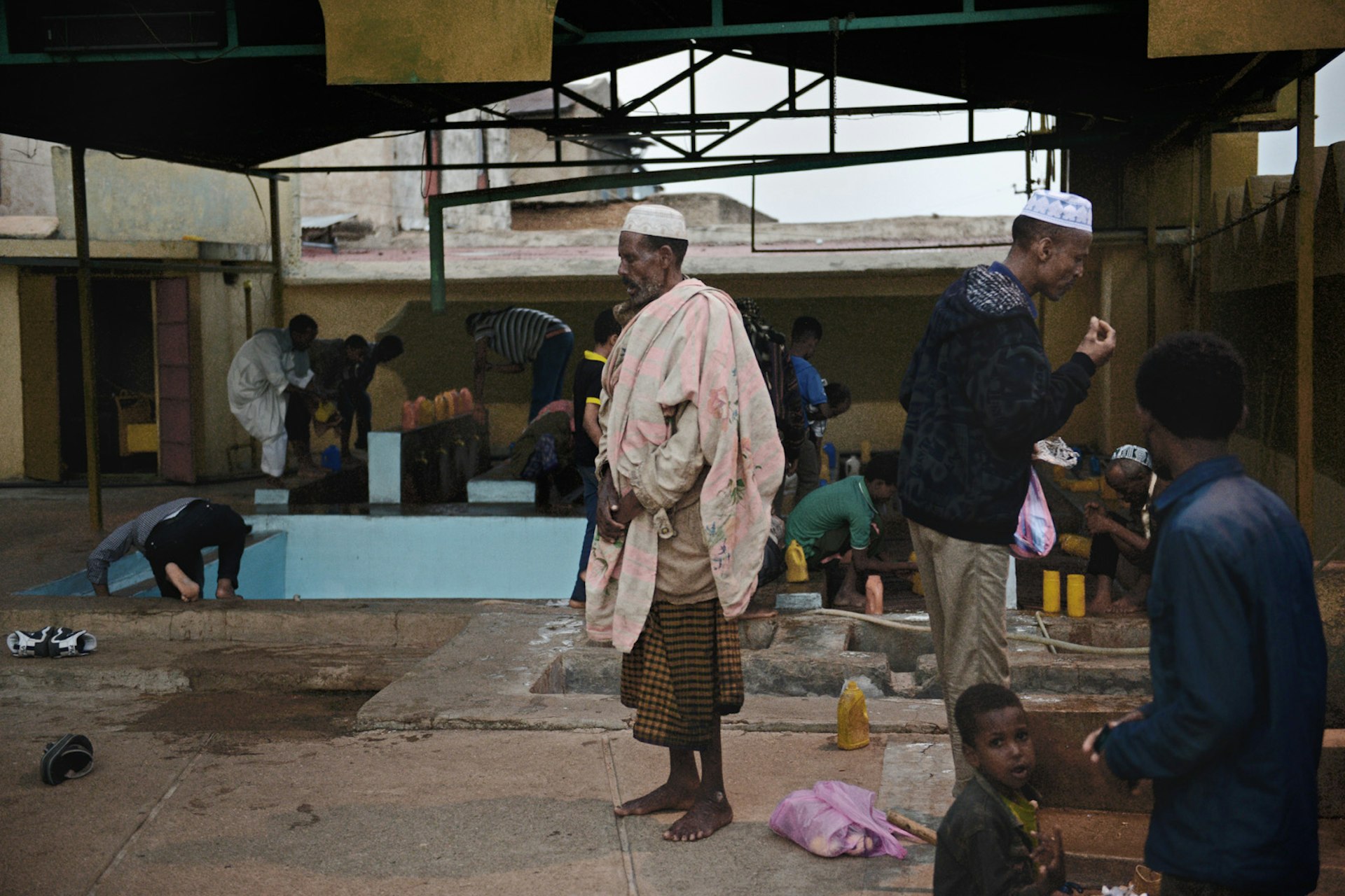 Ethiopian Muslims perform Wuḍū at a mosque in Harar, Ethiopia. Wuḍū is an Islamic obligatory procedure for washing parts of body (hands, mouth, ears, head, feet) before prayer.