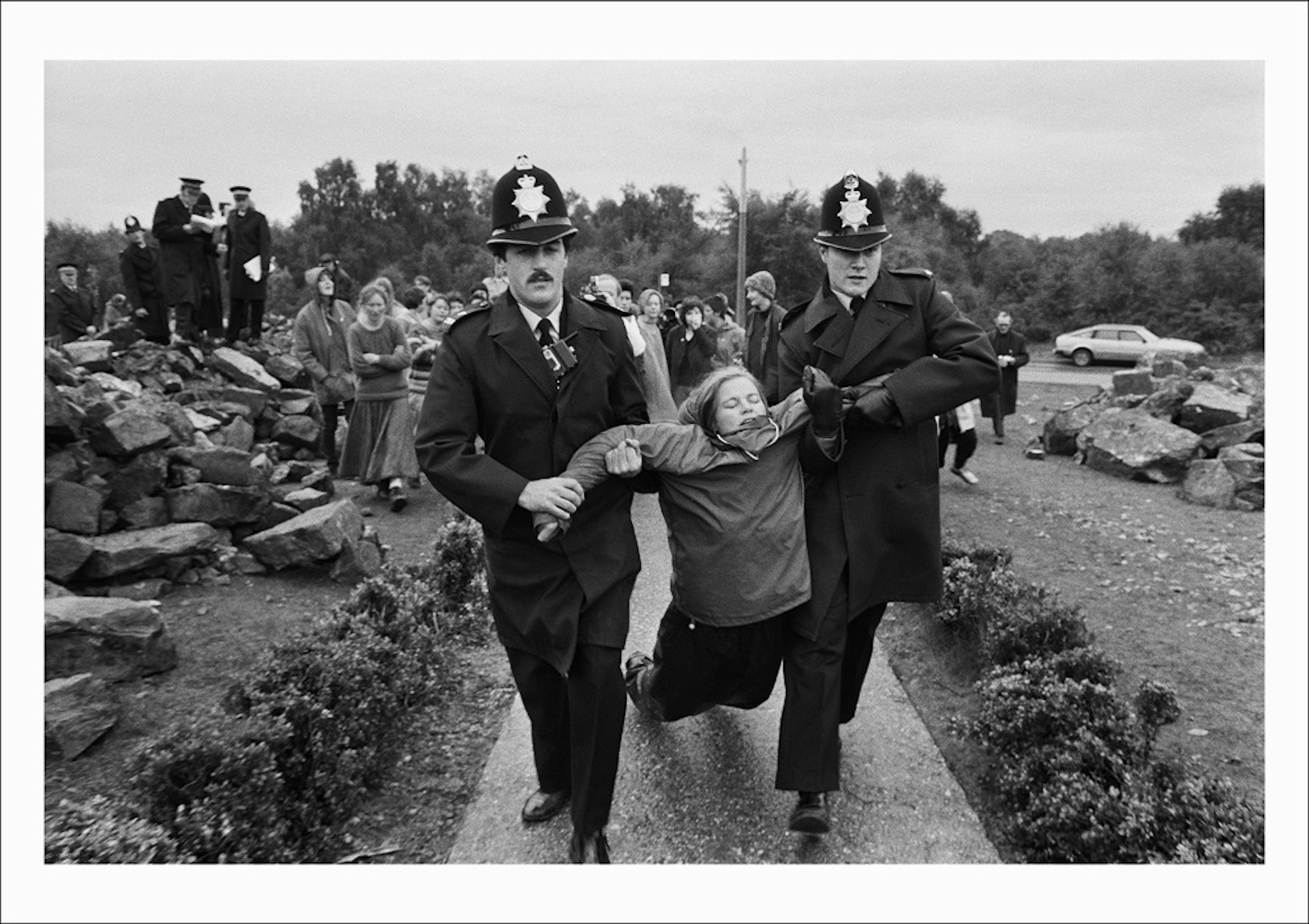 A protestor from the Women’s Peace Camp is arrested for obstructing building work outside the Main gate at RAF/USAF Greenham Common, Berkshire (1982) 