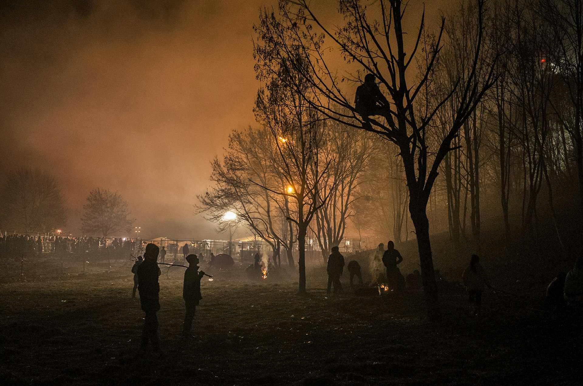 Šentilj, Slovenia, November 2015. After hours of waiting, groups of people move into a nearby field and use tree branches to make fires and keep warm.