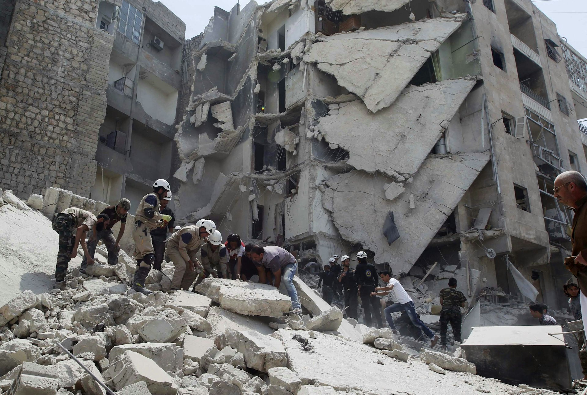 Civil Defence members, rebel fighters and civilians search for survivors at a site hit by what activists said was a barrel bomb in al-Qarlaq neighbourhood of Aleppo