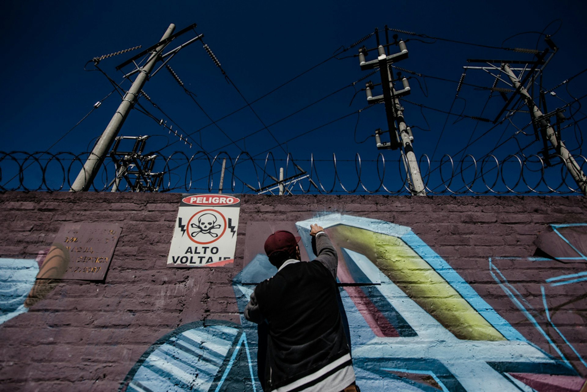 TNT tags the wall of a power station on the main street of Lourdes Colón, La Libertad, in full view of traffic.