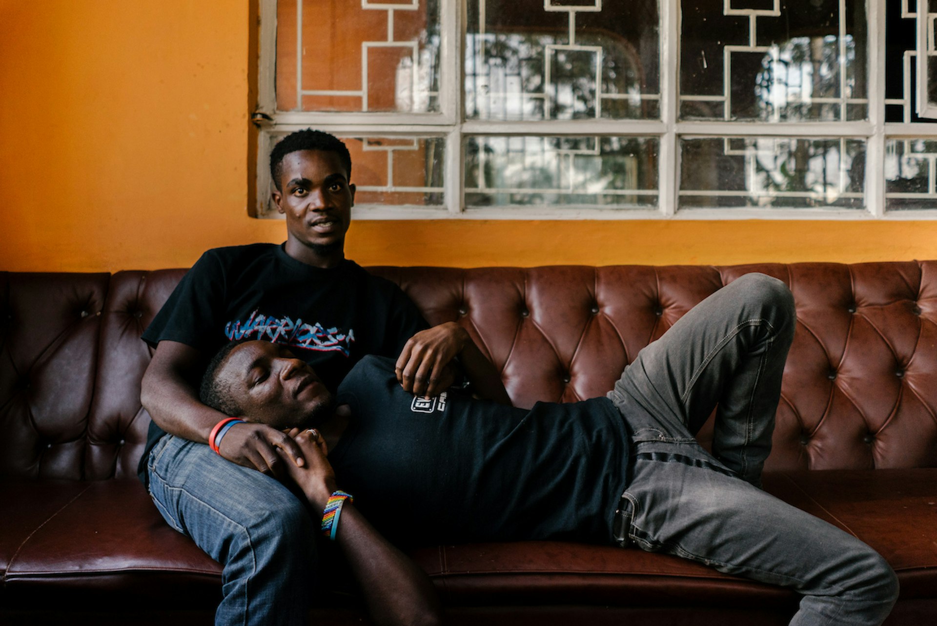 Nelson (lying down) and his boyfriend, who has since been resettled to the US, pose for a portrait at the gated house. Nelson studied theology and sexuality in Uganda and has made it his mission to keep morale in the house high. As such, he writes plays as well as organising games and dances.