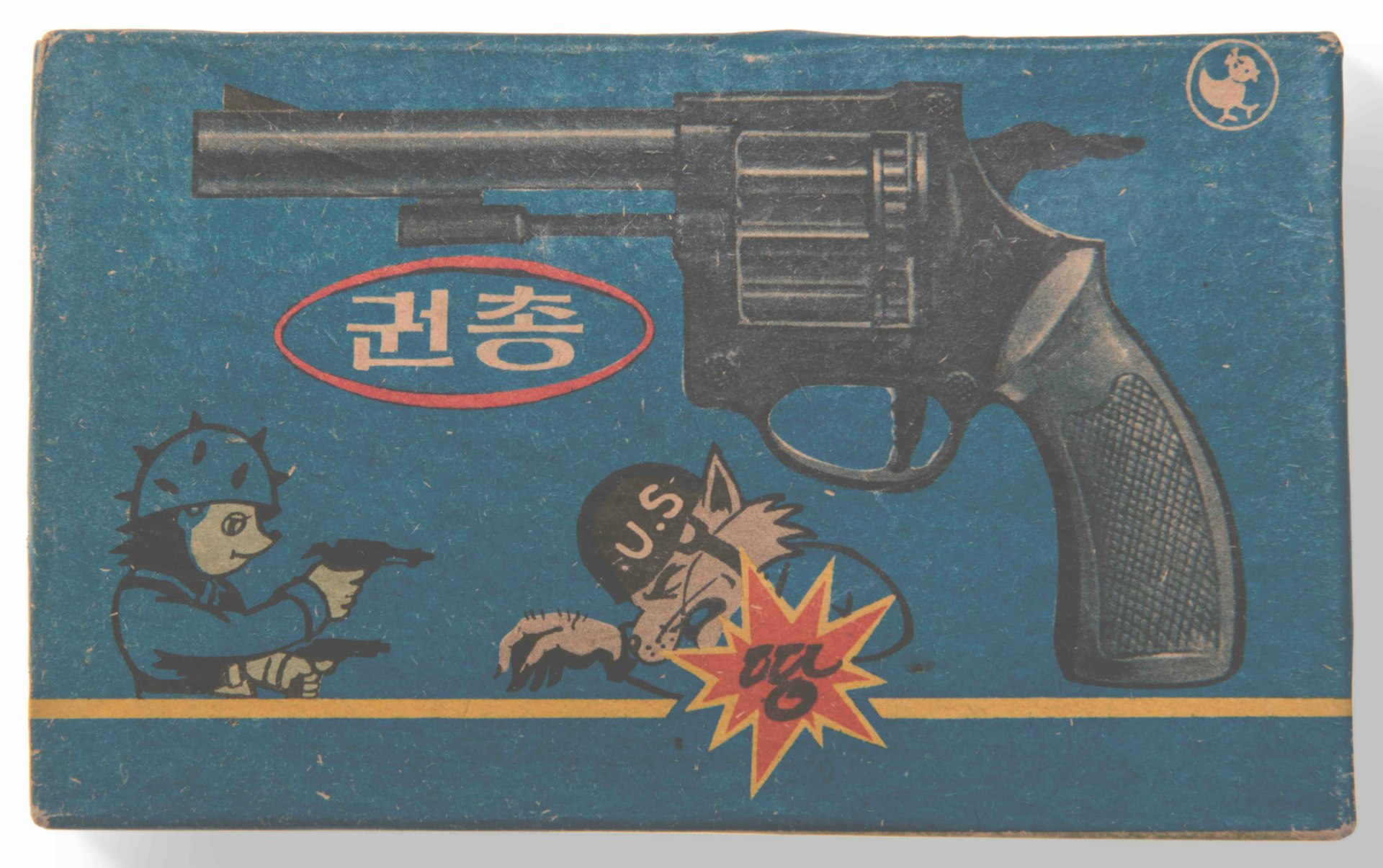 Box for a locally made toy gun that fires plastic bullets. The gun features the Korean Army slogan ‘Il Tang Paek’ meaning ‘one is the match for one hundred (enemies)’. The hedgehog is a popular cartoon character (representing the Korean hero) fighting the wolf and the weasel (representing the enemy  - the Americans). 