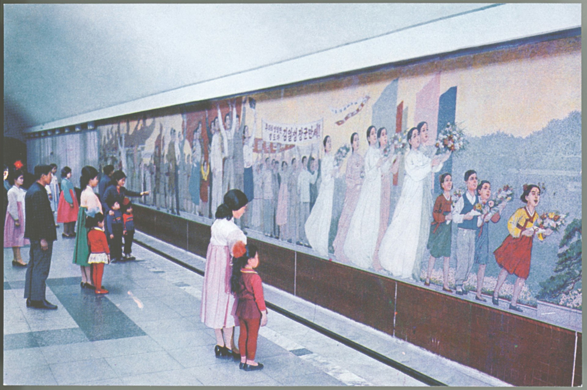 Card from a souvenir set of Pyongyang Metro postcards. In the 1990s and early 2000s there were rumours in the Western press that graffiti was being etched on to the windows of the Pyongyang Metro carriages. In fact, the carriages had been imported second-hand from West Berlin and the graffiti (impossible to remove from glass) was therefore in German.
