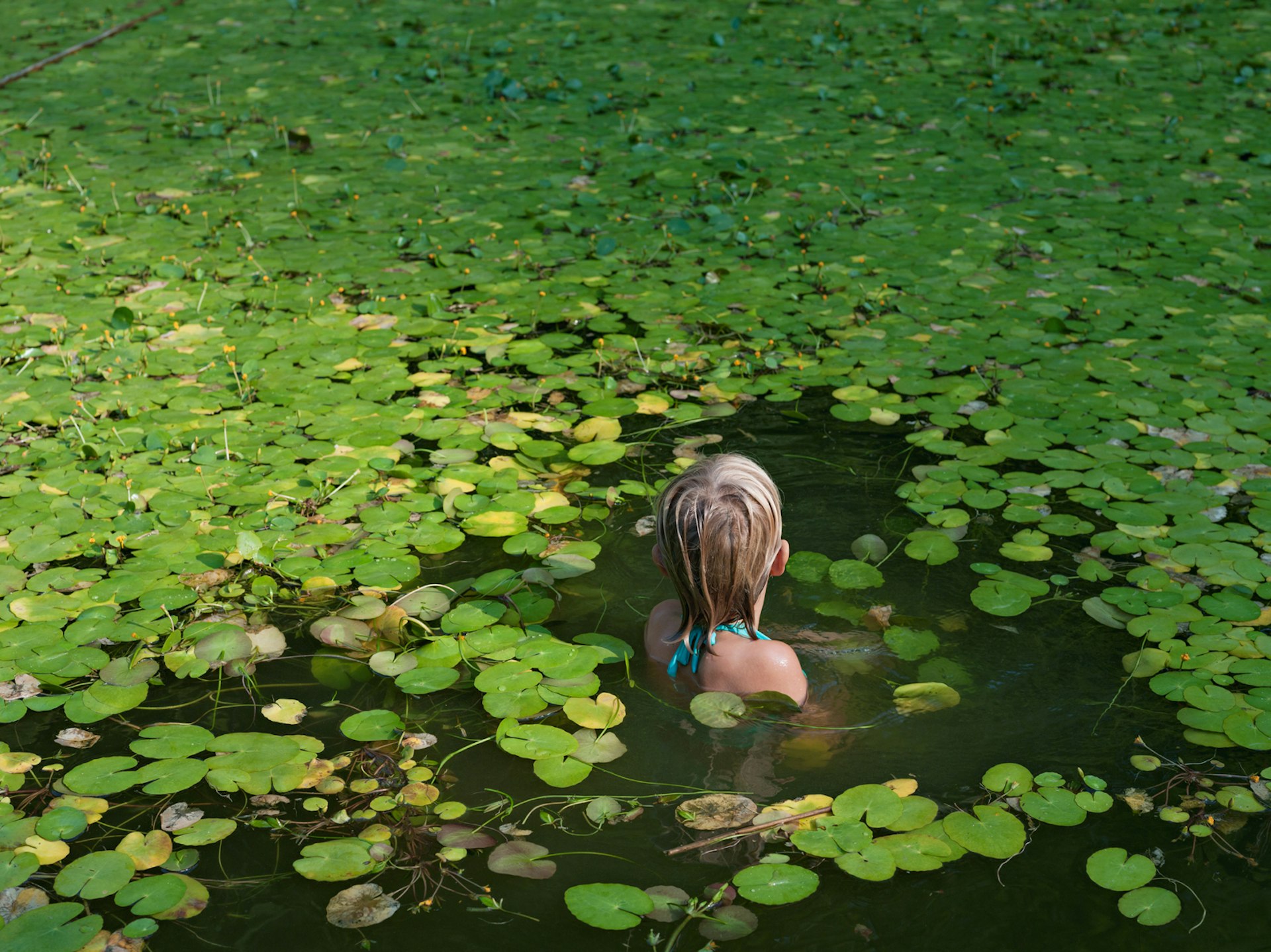 Maddie with invasive water lilies, North Carolina. © Lucas Foglia, courtesy of Michael Hoppen Gallery, London.