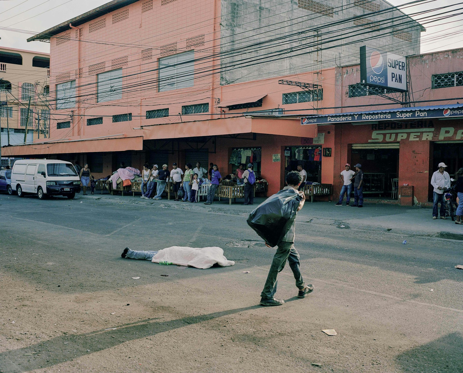 Merchants in San Pedro Sula, go about their business while a body lies in the middle of the street. Dead bodies sit for hours before the coroner has time to pick them up.
