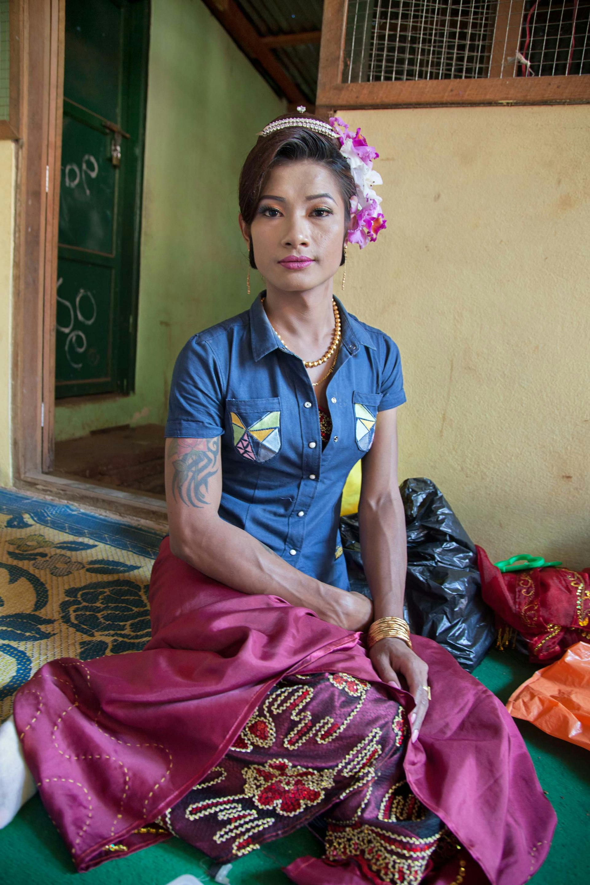 A gender variant tattooed and muscular nat kadaw in Mount Popa waits to perform at a nat pwe.