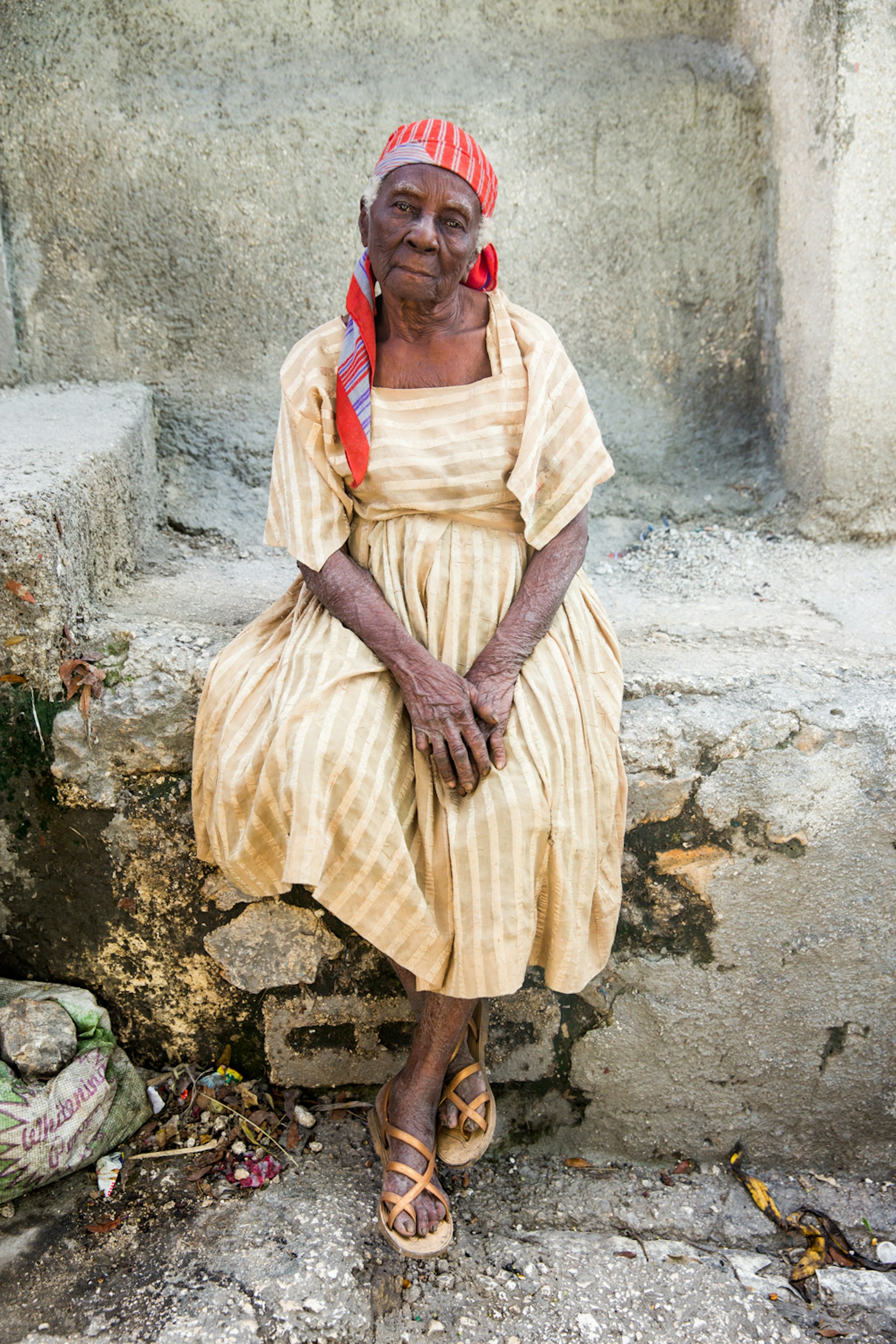 Frerisena Lagerre wearing a gold pin striped dress sits down to pose for a photo in Jalouzi, Petion-Ville.