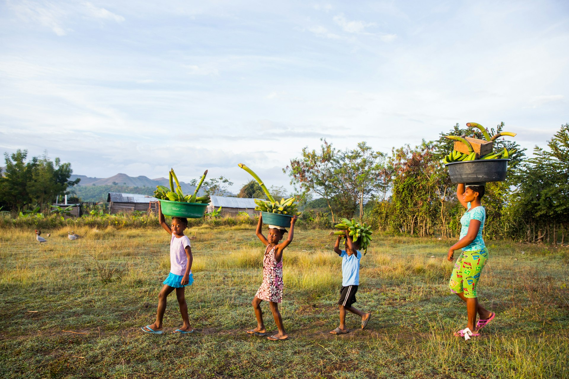 A family of banana farmers walk at sunrise in Central Plateau.