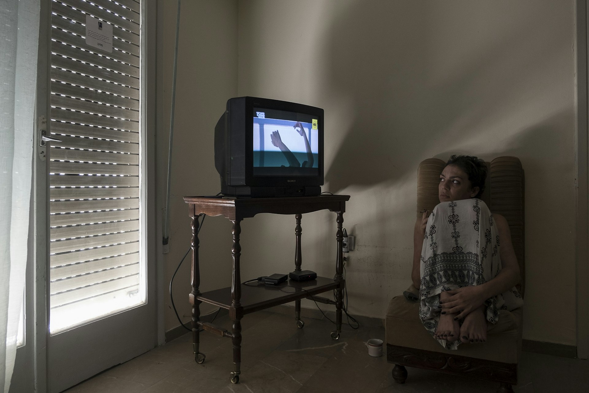 Y., 28, a transgender woman from Morocco watches TV while relaxing at her apartment in Athens, Greece. July 13, 2017