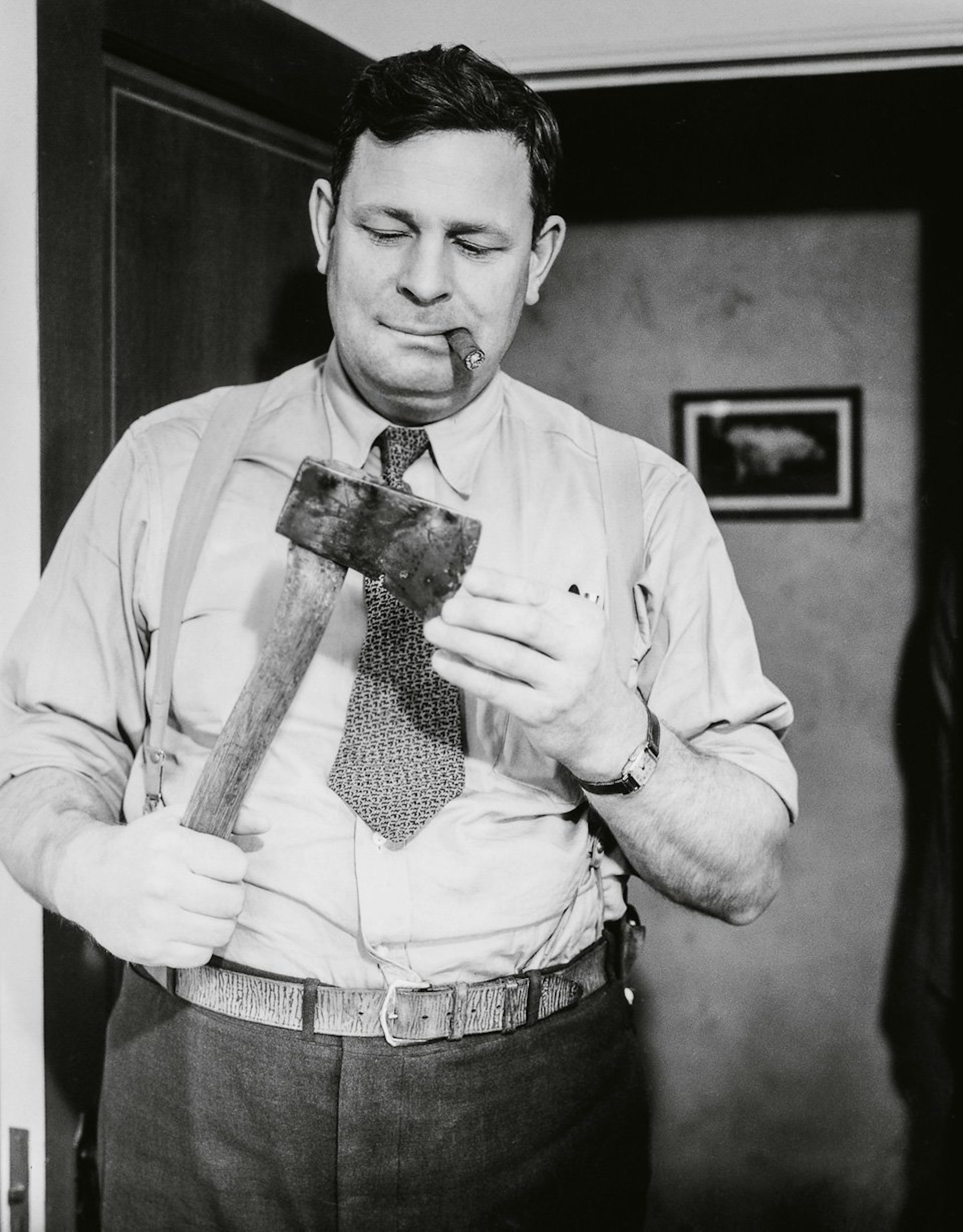 A cigar-chomping detective examines the murder weapon, ca. 1940. Copyright: Cliff Wesselmann Photo Courtesy of Gregory Paul Williams, BL Press LLC / TASCHEN