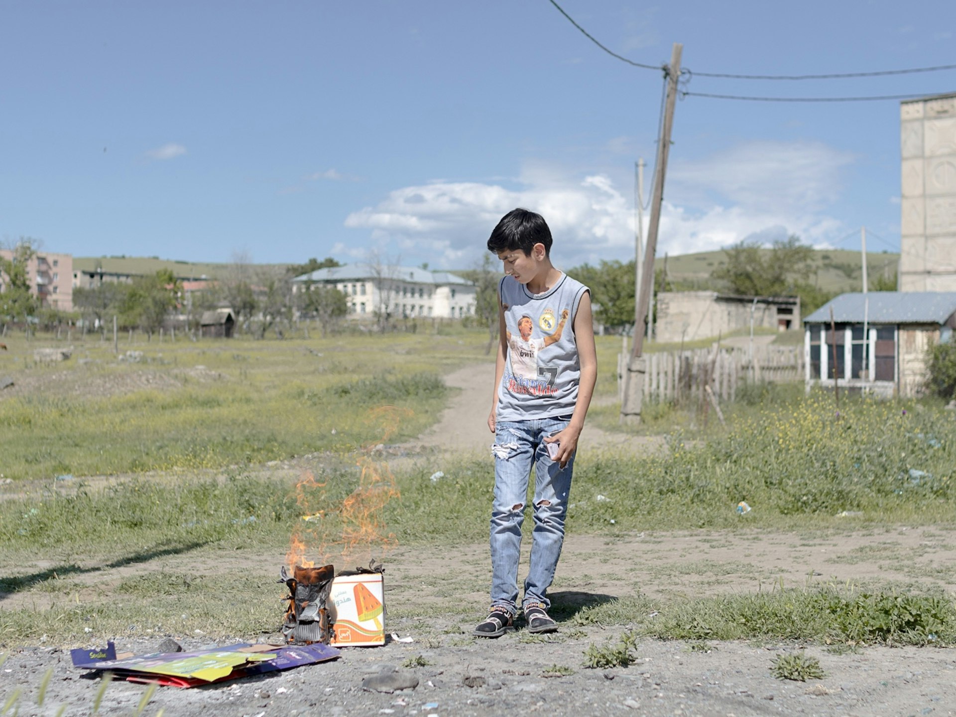 A boy burns collected garbage in the center of the settlement. Children struggle to find activities in Vaziani. The parents in the settlement worry about the future of their kids, thus they try to give them better prospects in life through education.