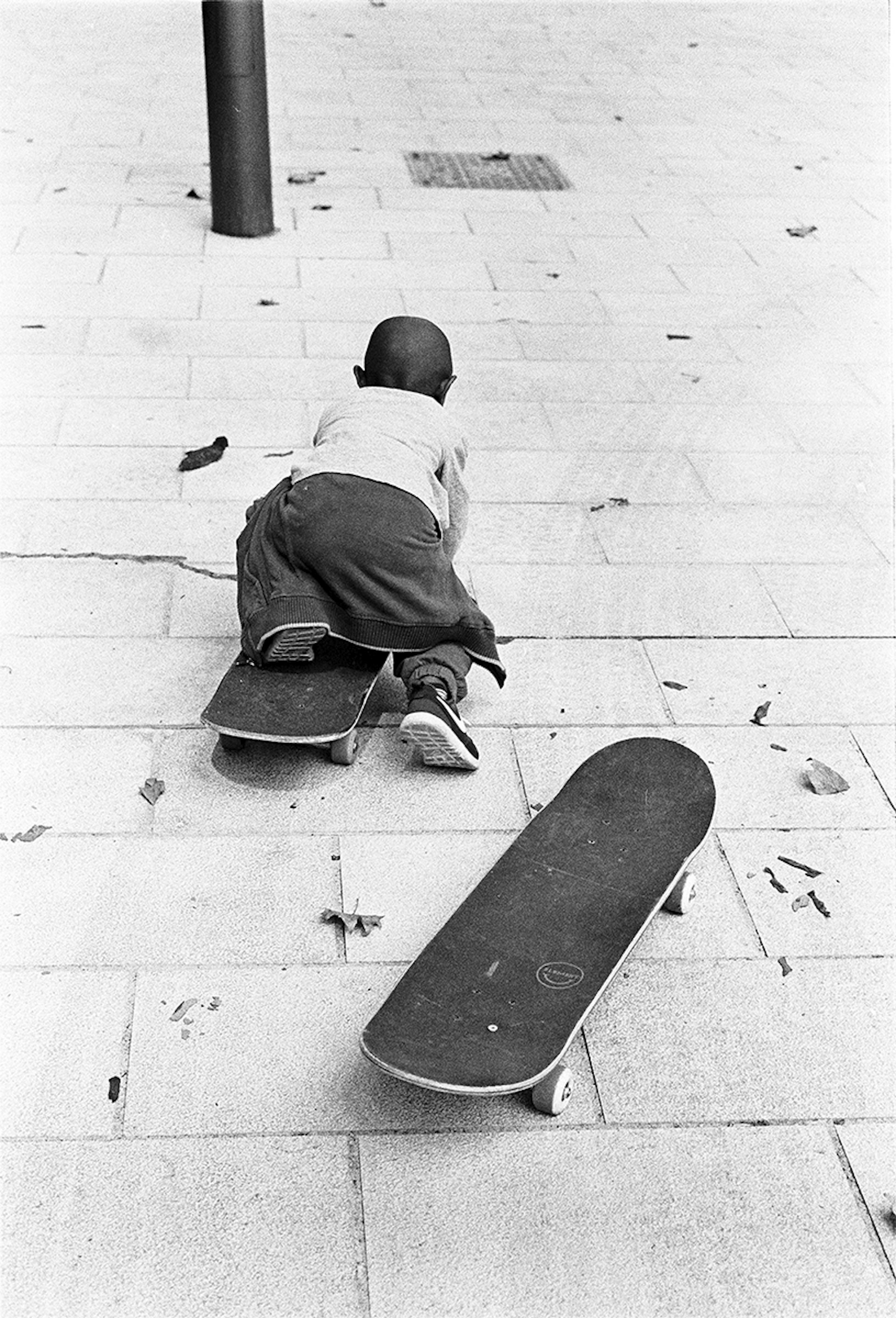 A young boy lies on a skateboard and pushes themself along