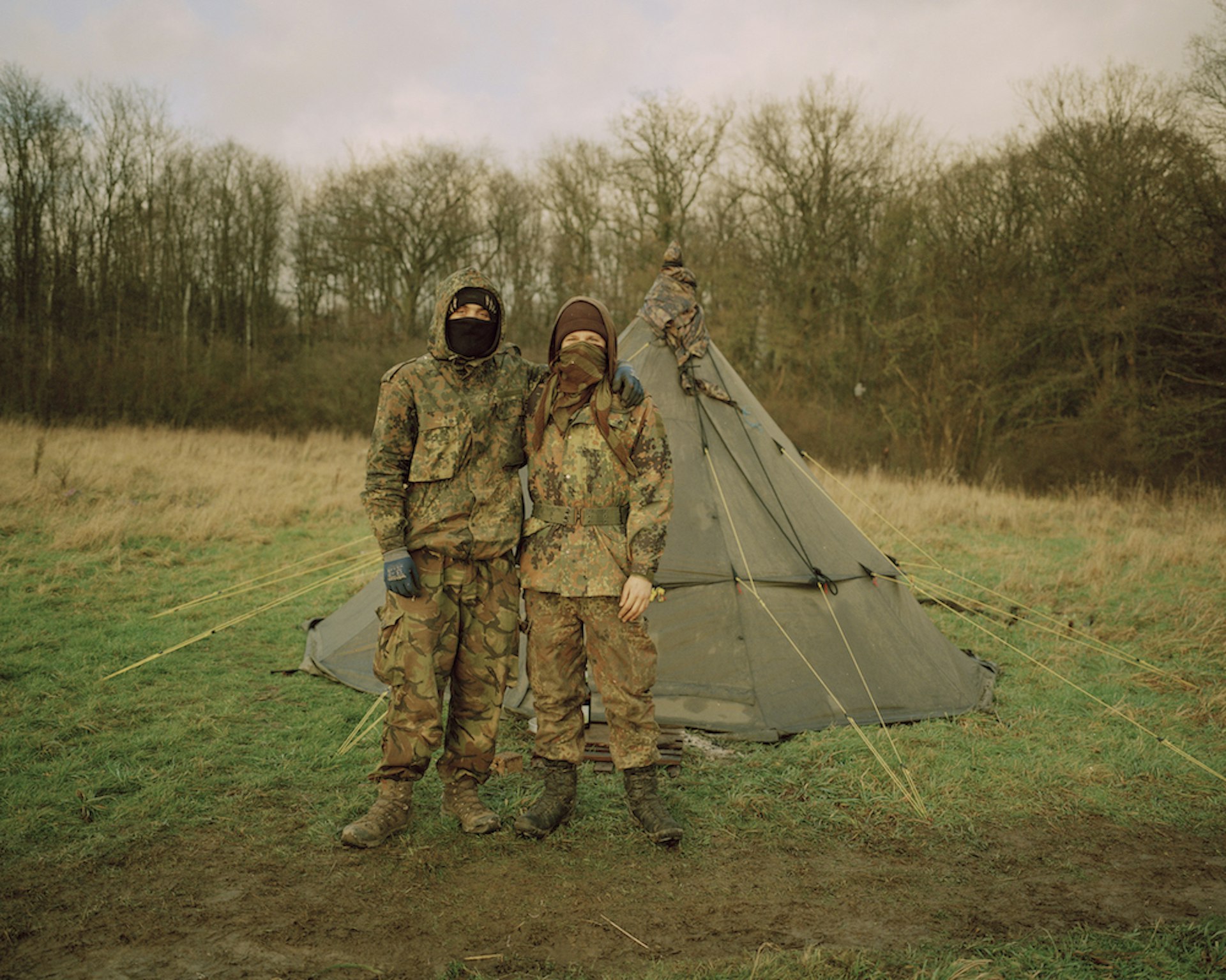 Two ecoactivists in camouflage pose in front of their tent