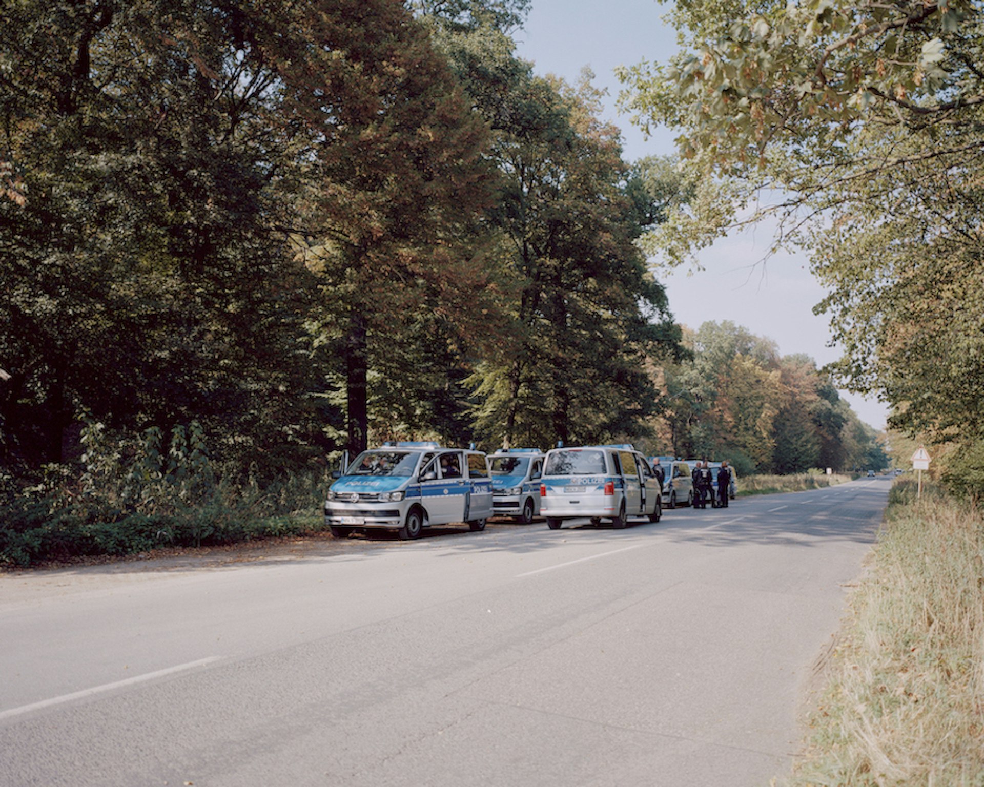 A row of police vehicles line up along the side of the road at Hambach Forest