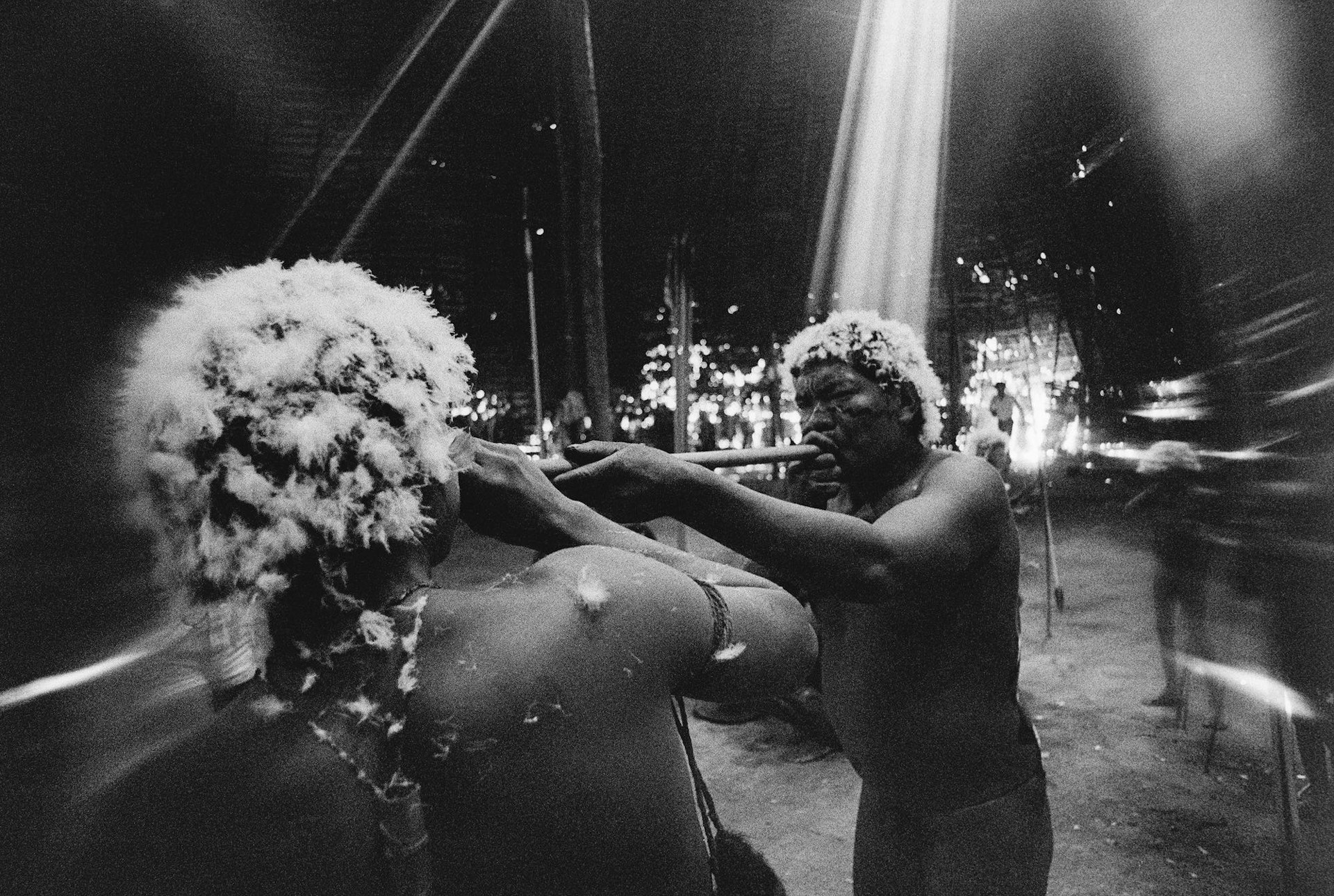 Amazon The shaman Tuxaua João blows on the hallucinogen yãkoana in the nostrils of a young man at the end of the reahu feast, Catrimani, Roraima, 1974